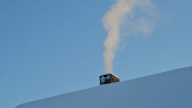 Dymiący komin na dachu pokrytym śniegiem