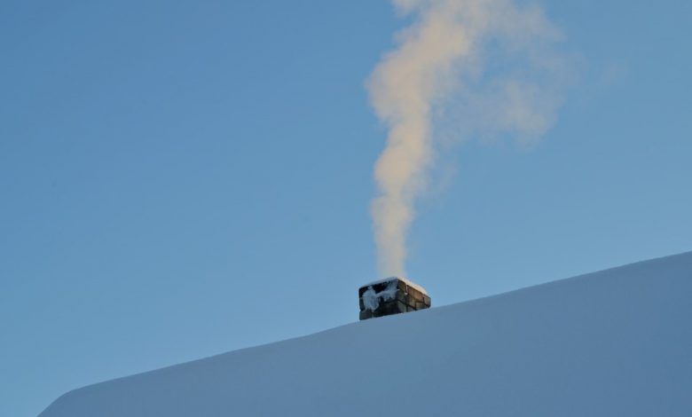 Dymiący komin na dachu pokrytym śniegiem